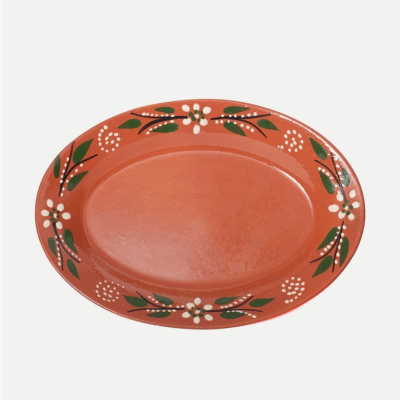 Prato oval em cerâmica com decoração floral em branco, verde e preto numa base terracota