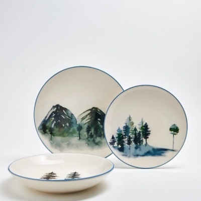 Conjunto de pratos de cerâmica com ilustrações de árvores e montanhas.
