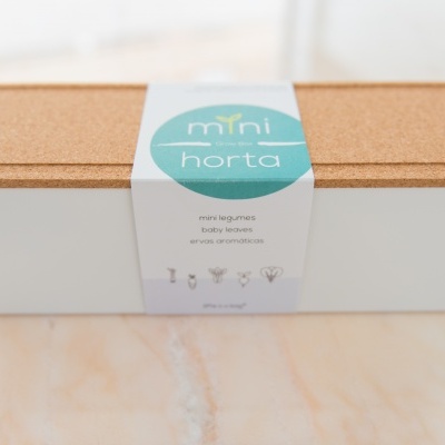 Caixa branca com tampa de cortiça e etiqueta 'mini horta'