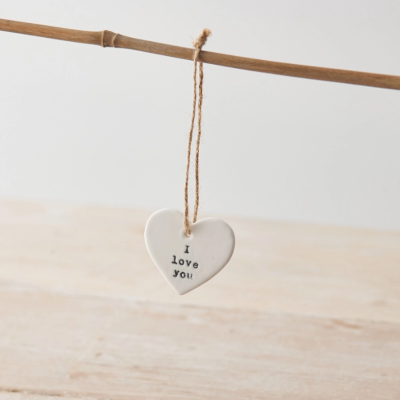 Pendente de coração branco com texto 'I love you' pendurado num ramo.