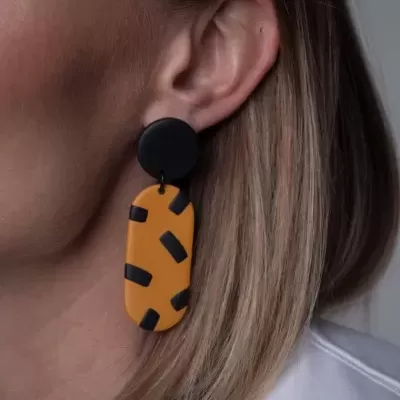 Brinco pendente laranja com manchas pretas e peça redonda preta