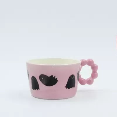 Chávena rosa com desenhos pretos de pássaros e pega redonda em bolas