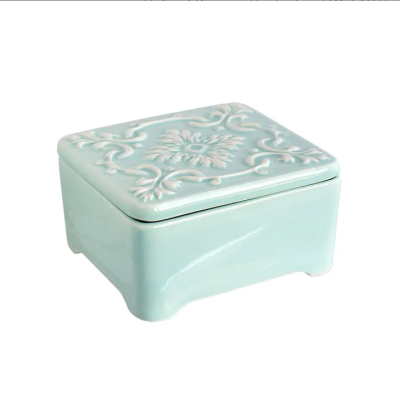 Caixa quadrada azul clara de cerâmica com tampa decorada em relevo.