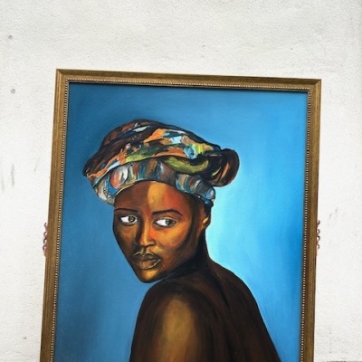 Pintura em moldura dourada de mulher negra com turbante colorido e fundo azul