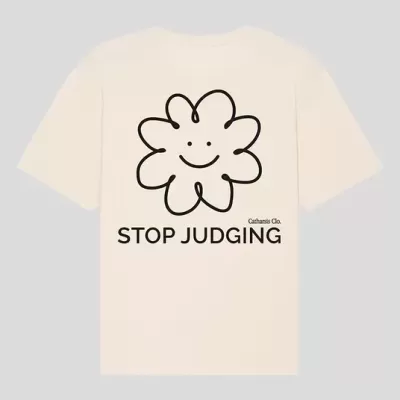 T-shirt de algodão bege com estampado de flor sorridente e o texto STOP JUDGING