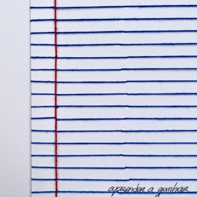 tecido branco com linhas azuis e vermelhas e texto bordado