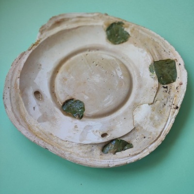 Prato cerâmico branco com manchas verdes e bordas danificadas