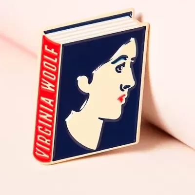 Pin metálico em forma de livro com capa azul e texto 