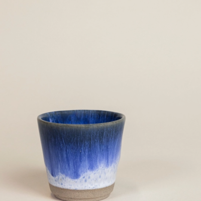 Copo pequeno cerâmico azul e branco em fundo bege