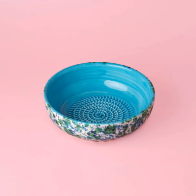 Taça cerâmica azul com padrão decorativo exterior colorido sobre fundo rosa