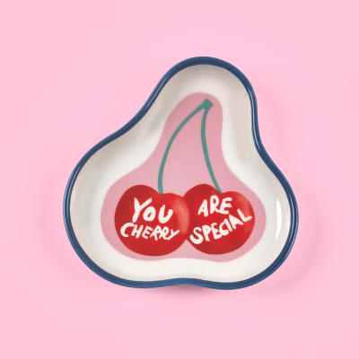 Prato decorativo com ilustração de cerejas e texto em inglês, sobre fundo rosa.