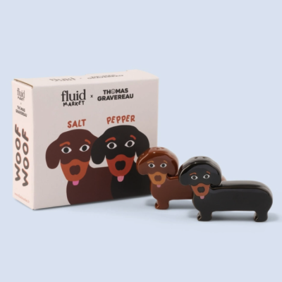 Conjunto de saleiro e pimenteiro em cerâmica com forma de cães castanho e preto com caixa desenhada.