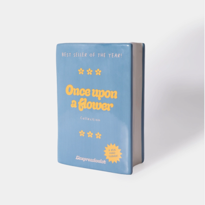 Objeto cerâmico azul em forma de livro com texto amarelo e branco