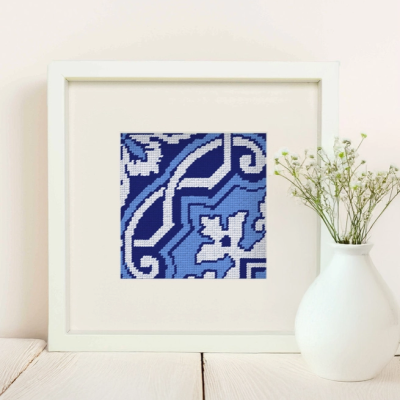 Quadro branco com bordado azul decorativo e vaso com flores pequenas