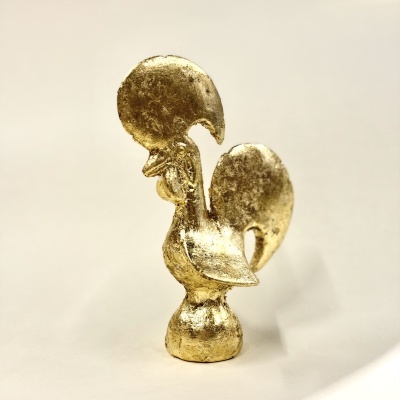 Estatueta dourada de galo sobre fundo claro