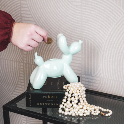 Cofre cão cerâmica branca sobre livro com colar de pérolas