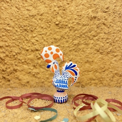 Figurinha de galo em cerâmica pintada com fitas de papel ao redor