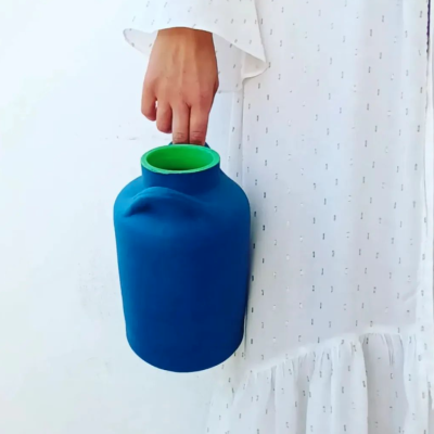 Balão térmico azul com interior verde segurado por uma mão com vestido branco com padrões