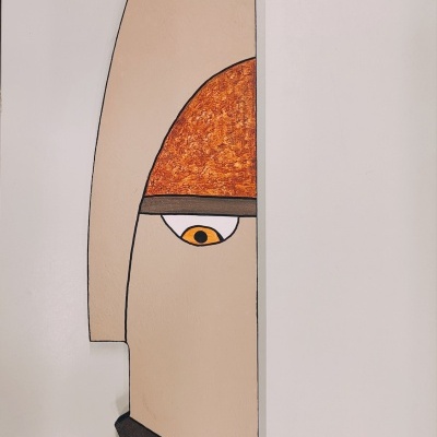 Escultura estilizada de rosto humano em parede com várias cores e texturas