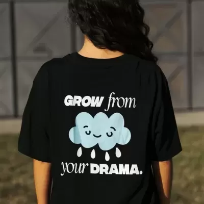 Pessoa com t-shirt preta com estampa de nuvem sorridente e texto em inglês na parte de trás.