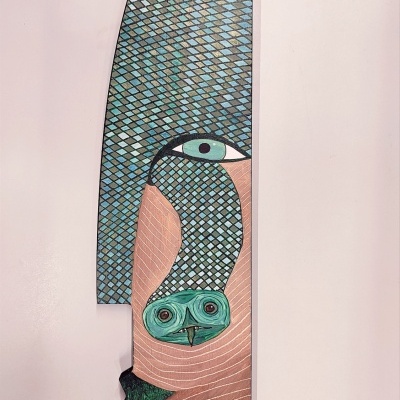 Escultura decorativa de rosto estilizado com padrão de escamas azuis e bege