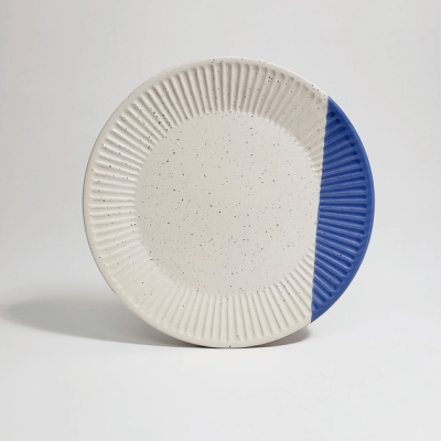 Prato cerâmico redondo branco com manchas e parte azul texturada.