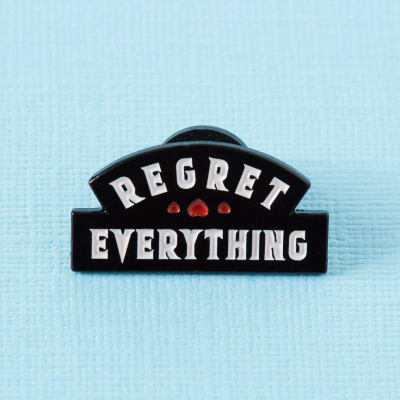 Pin preto com texto REGRET EVERYTHING e três corações vermelhos em fundo azul claro
