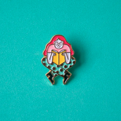 Pin metálico de mulher a ler livro com cabelo vermelho