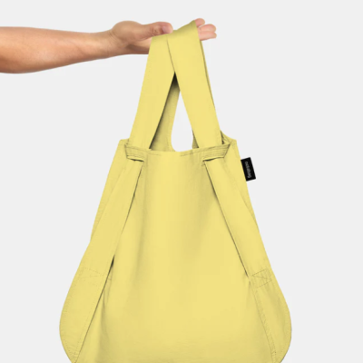 Mala reutilizável amarela de pano com alças largas e etiqueta preta