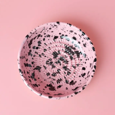 Prato redondo rosa com manchas pretas e textura concêntrica