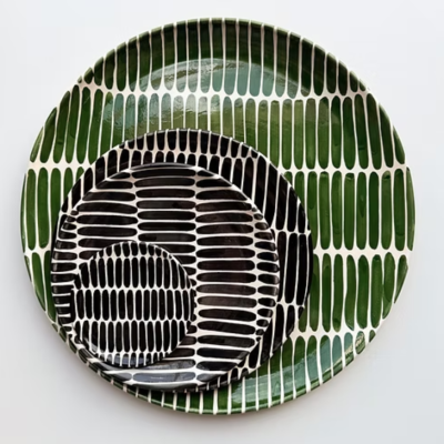 Três pratos de cerâmica com padrões geométricos em preto, verde e branco