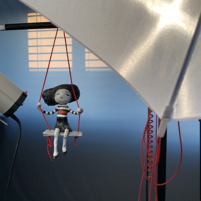 Boneca pendurada num baloiço com luzes e fundo azul