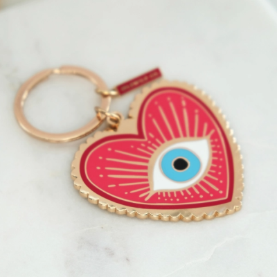 Porta-chaves coração dourado e vermelho com desenho de olho azul e texto BAN.DO