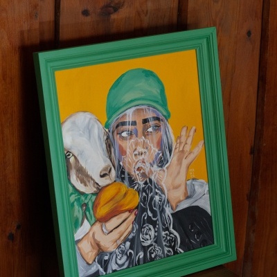 Quadro pintado de figura humana com gorro verde e animal branco sobre fundo amarelo com moldura verde.