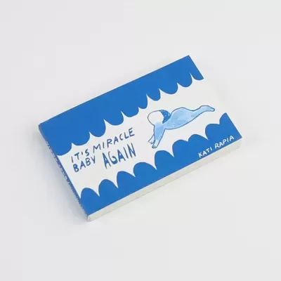 Livro azul e branco com desenho de bebé a nadar e texto IT'S MIRACLE BABY AGAIN, KATI RAPIA