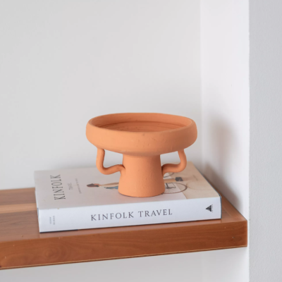 Prato decorativo de terracota sobre livros na prateleira