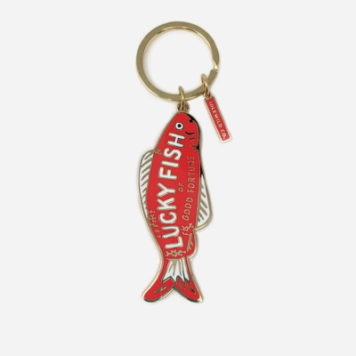 Porta-chaves metálico em forma de peixe vermelho com texto e pendente vermelho.