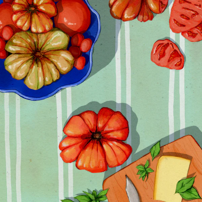 Tomates de várias cores e tamanhos, tábua de madeira com queijo e faca, folhas verdes sobre pano verde às riscas.
