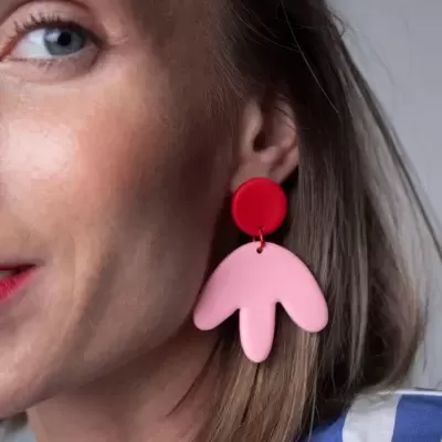Brinco pendente vermelho e rosa em orelha feminina