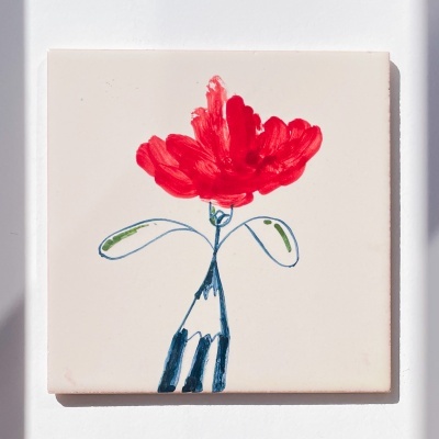 Azulejo quadrado branco com desenho de flor vermelha e folhas verdes