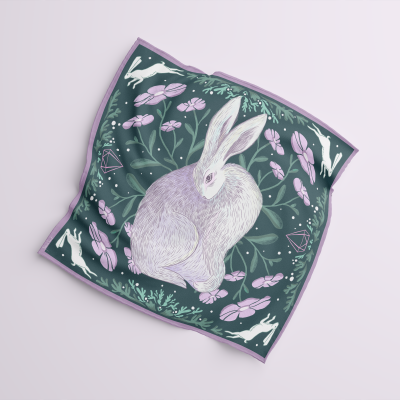 Lenço quadrado com ilustração de coelho, flores e folhas em tons lilás, verde e branco.