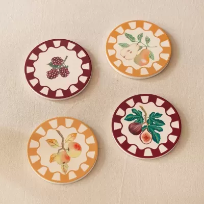 Bases para copos redondas decoradas com ilustrações de frutas sobre tecido bege.