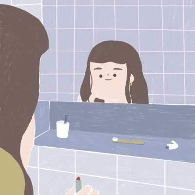 Pessoa a aplicar batom vermelho junto a espelho de casa de banho com escova de dentes dourada e auriculares brancos