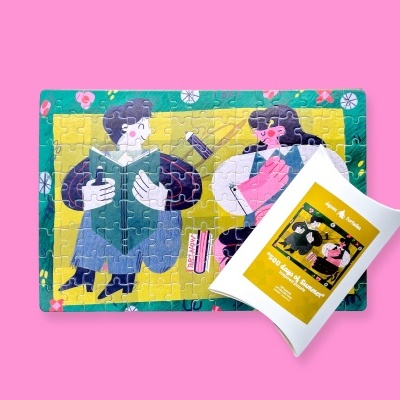 Quebra-cabeças ilustrado com duas personagens a ler e embalagem branca com etiqueta amarela