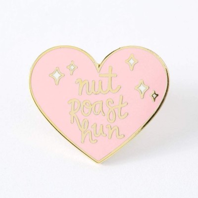 Pin em forma de coração cor-de-rosa com texto dourado 'nut roast hun' e estrelas douradas