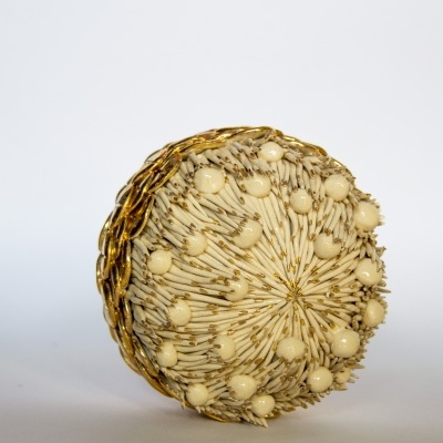 Pente redondo decorativo dourado e creme sobre fundo branco