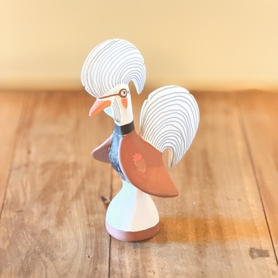 Figura decorativa de galo em madeira sobre superfície de madeira clara
