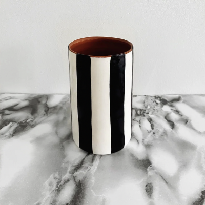 Vaso cerâmico listrado preto e branco em superfície marmoreada