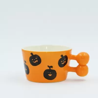 Caneca de cerâmica laranja com abóboras pretas e punho de duas bolas