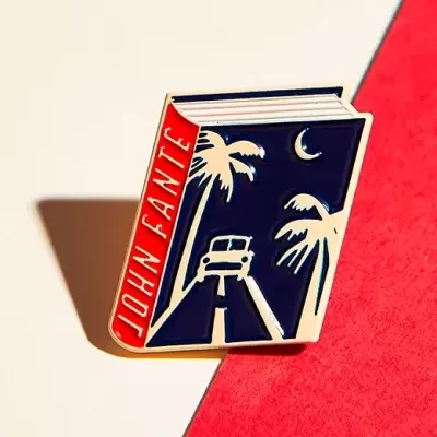 Pin metálico com design de livro e texto JOHN FANTE